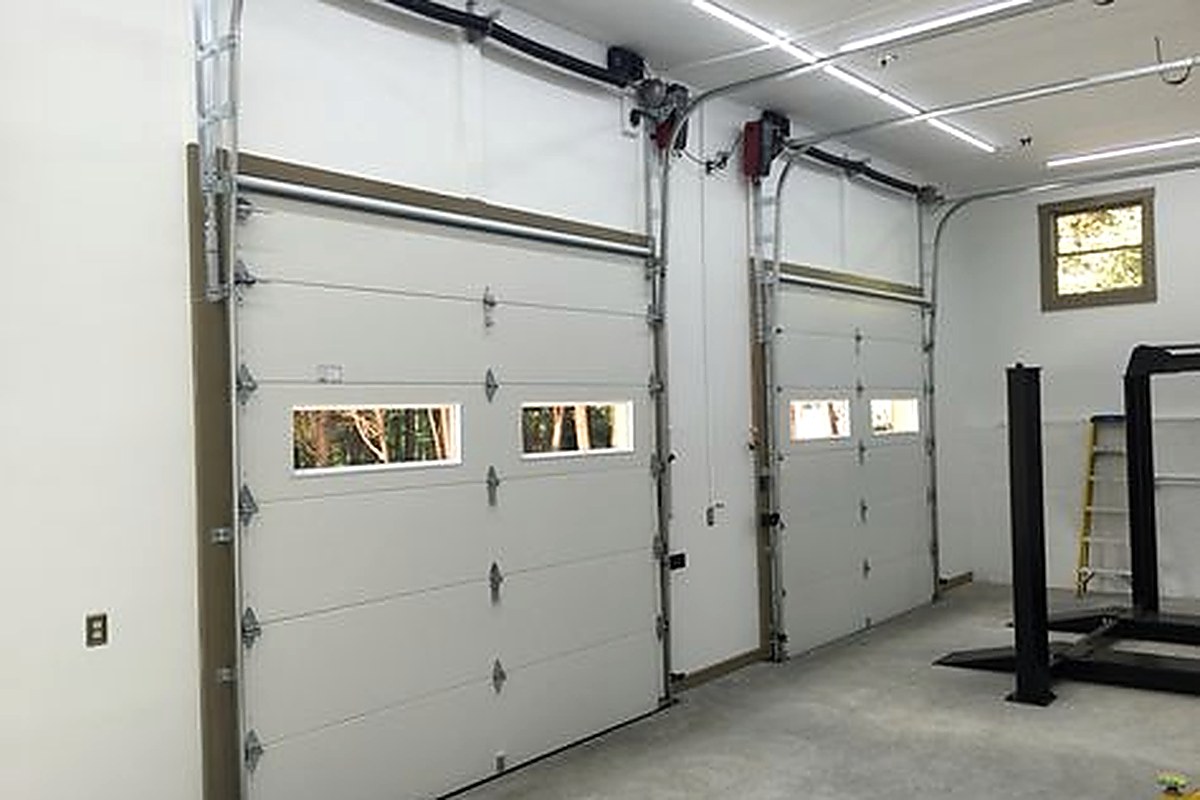 High lift garage door installation with raised track and a car lift alongside